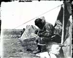 Inuit with flint drill outside skin tent